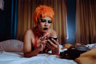 Serious young ethnic woman using smartphone lying on bed