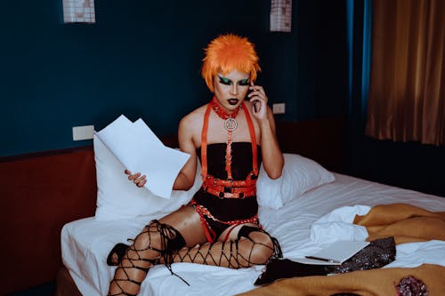 Provocative actress in bondage speaking on smartphone in hotel room