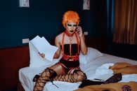 Provocative actress in bondage speaking on smartphone in hotel room