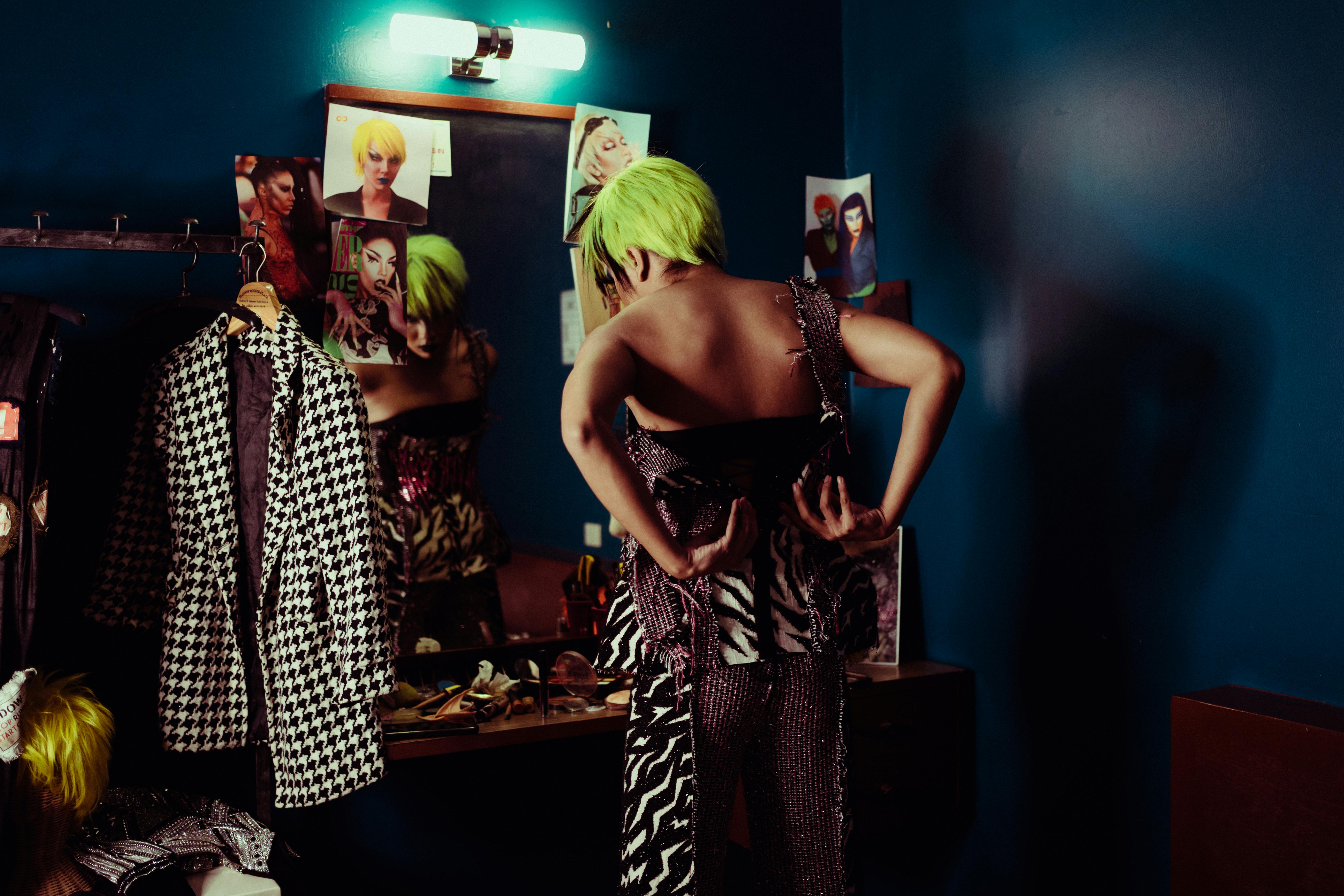 trendy actress putting on clothes near mirror in makeup room