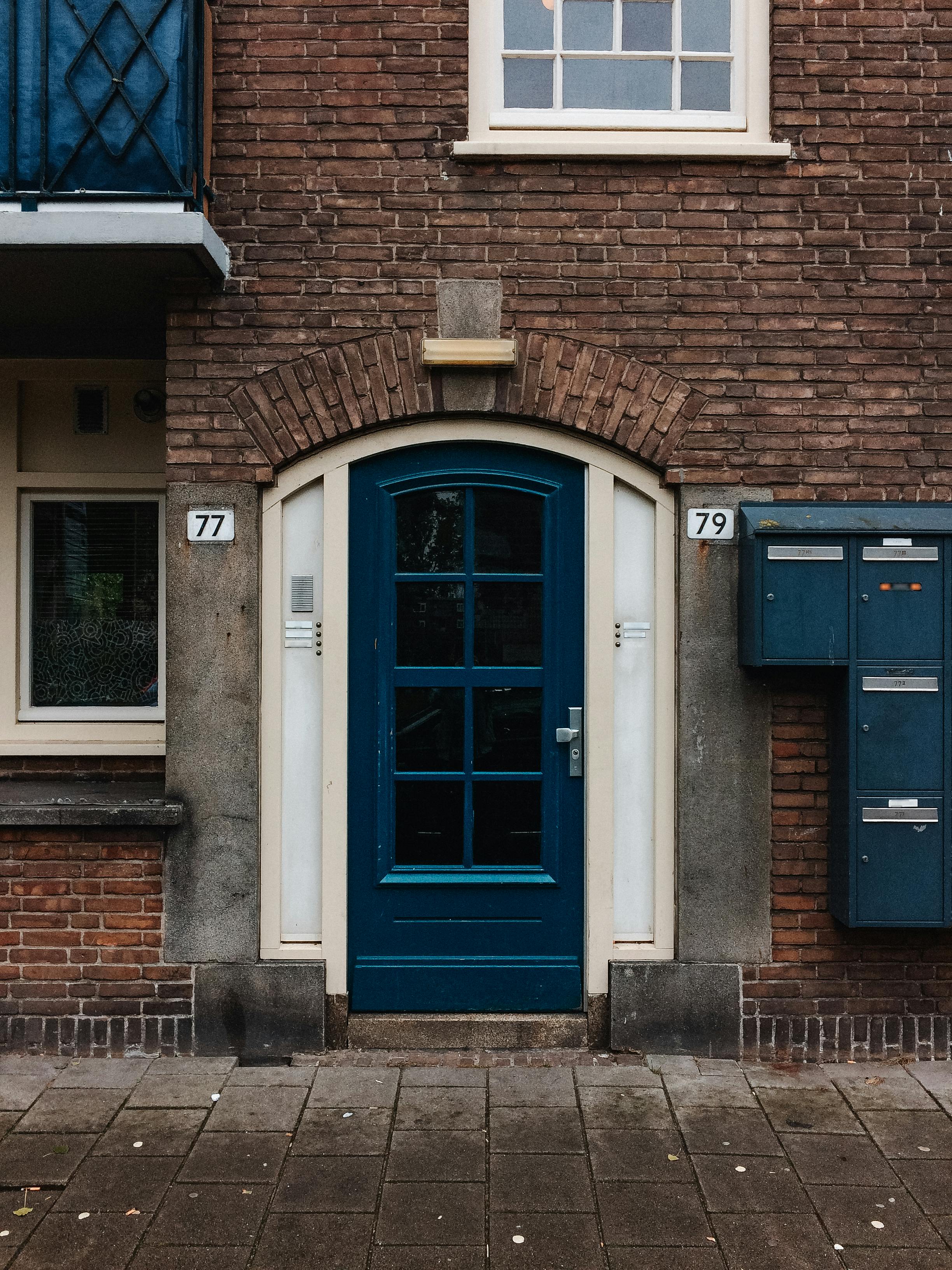 Charming entrance with blue wooden door and brick wall facade on urban street.