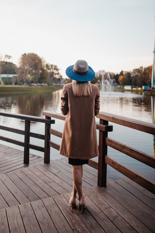 棕色外套站在木碼頭上的女人