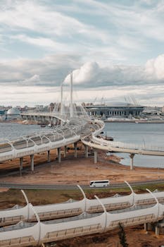Dynamic aerial view of a contemporary bridge spanning a river in an urban cityscape.