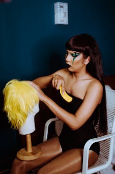 A makeup artist focuses intently on styling a vibrant yellow wig indoors.