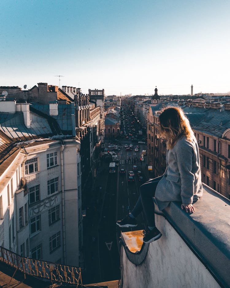 Woman Sitting On A Building Ledge 