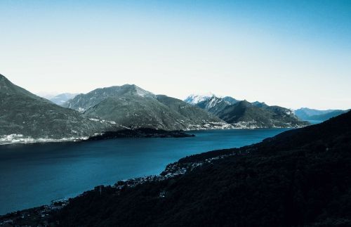 Free Stunning scenery of blue calm river running through coast with rocky rough mountains with snowy peaks under cloudless blue sky Stock Photo