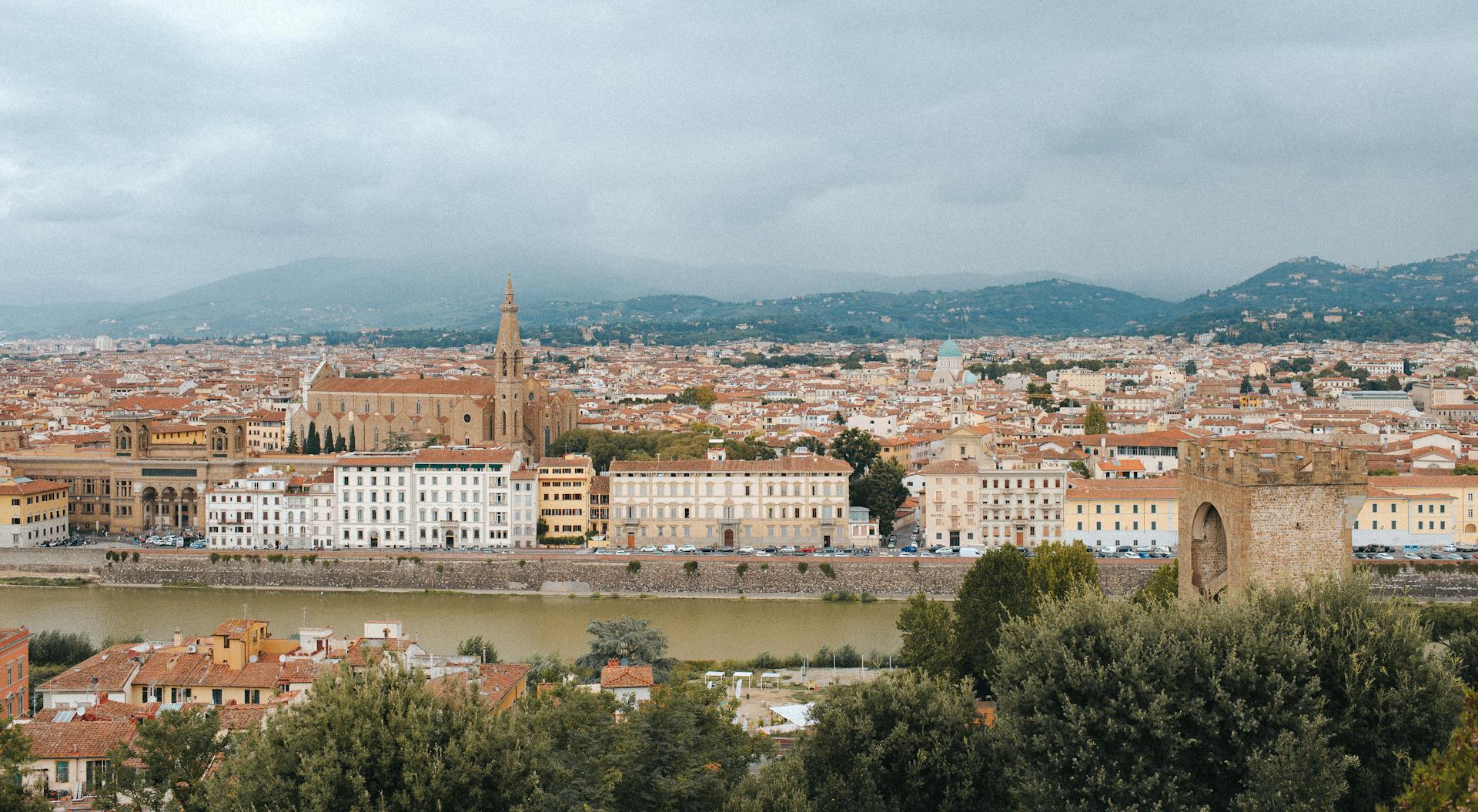 Scenic view of Florence with historic architecture and Arno River under a cloudy sky.