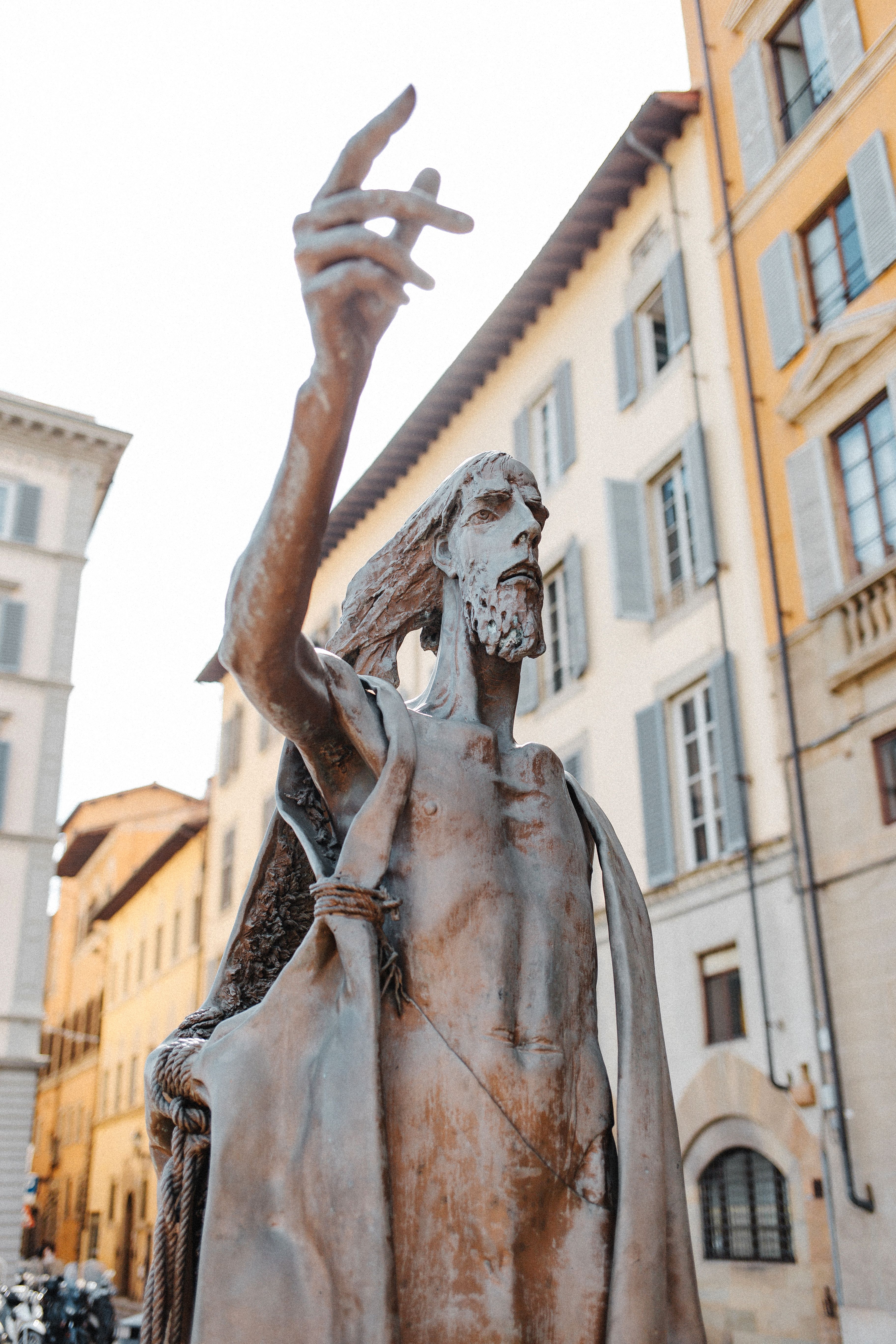 Elegant sculpture of St John the Baptist in a bustling Italian city square, perfect for tourism and culture themes.