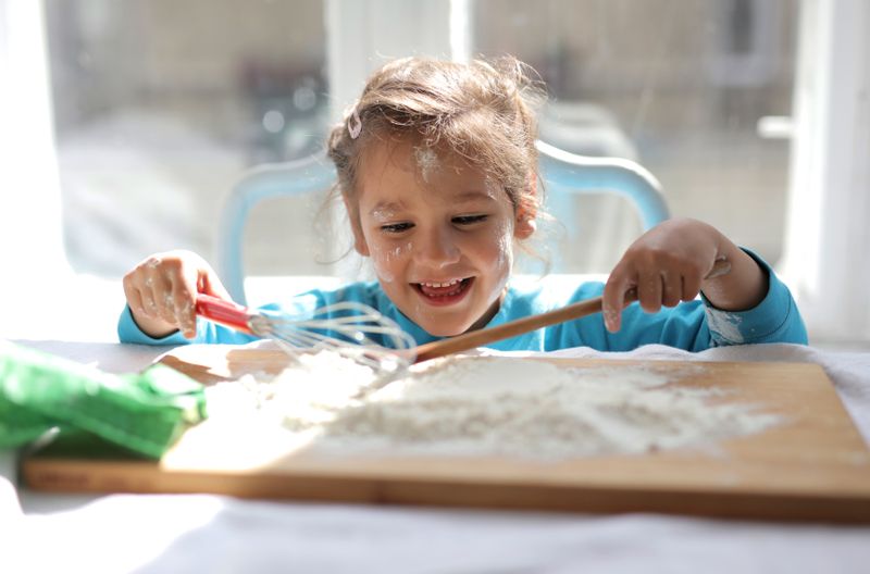 Little baker playing happily with flour and kitchen tools