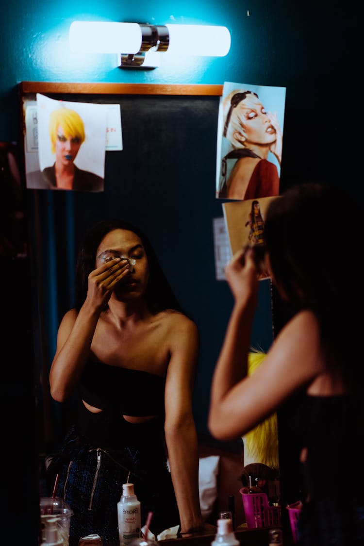 Ethnic Woman Removing Makeup Against Mirror