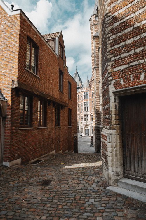 Free Explore a quaint cobblestone alley flanked by historic brick buildings in a picturesque old town setting. Stock Photo