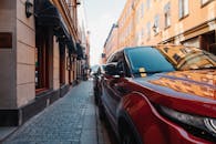 鹅卵石街道上停着一辆明亮的红色汽车，两旁是建筑物和柔和的光线