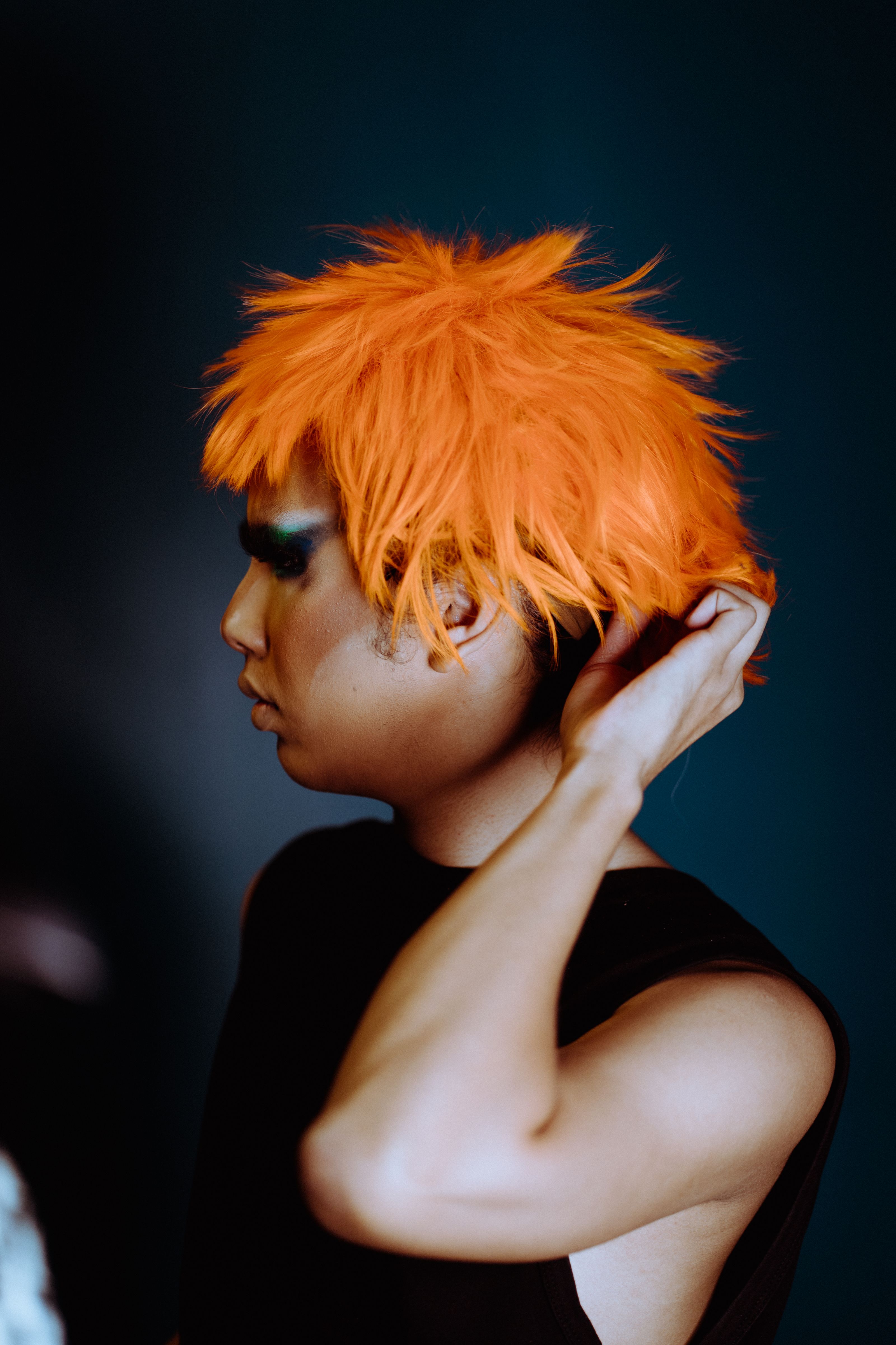 A person adjusting a bright wig in a studio