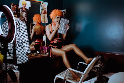 Bizarre woman applying black lipstick in dark room