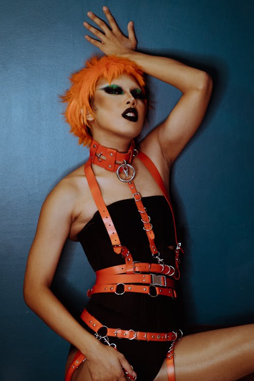 Provocative woman with orange hair in bodysuit standing alluringly