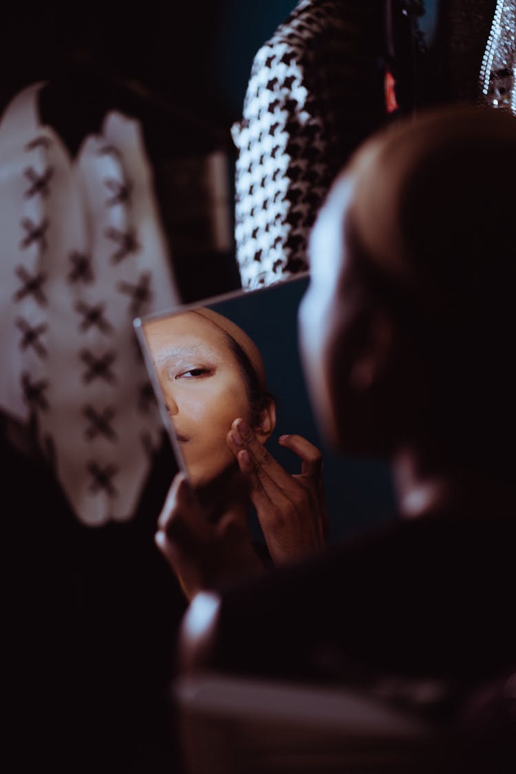 Crop Androgynous Woman Applying Skin Foundation In Dark Room