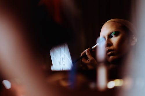 Calm transsexual woman applying eye makeup