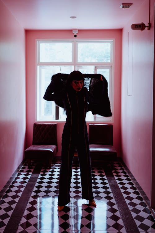 Informal funky woman in black suit standing in hallway