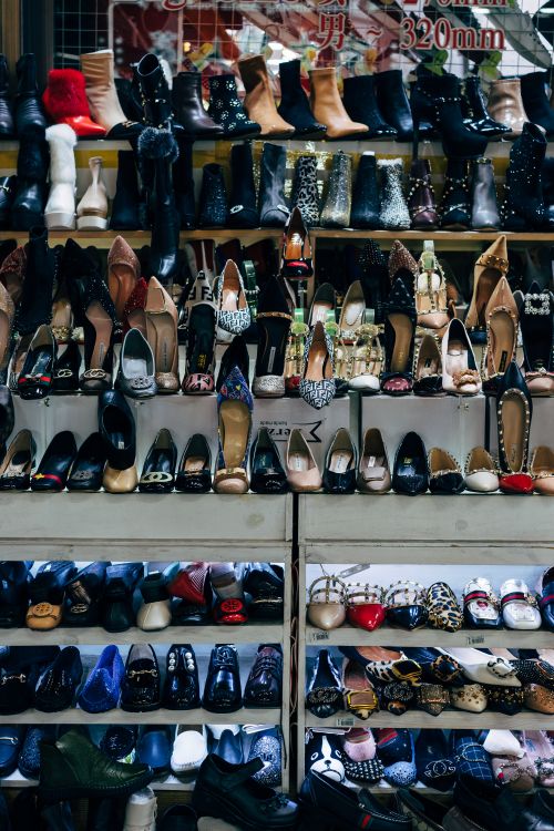 Free Colorful array of footwear on shelves showcasing diverse styles in an Asian night market. Stock Photo