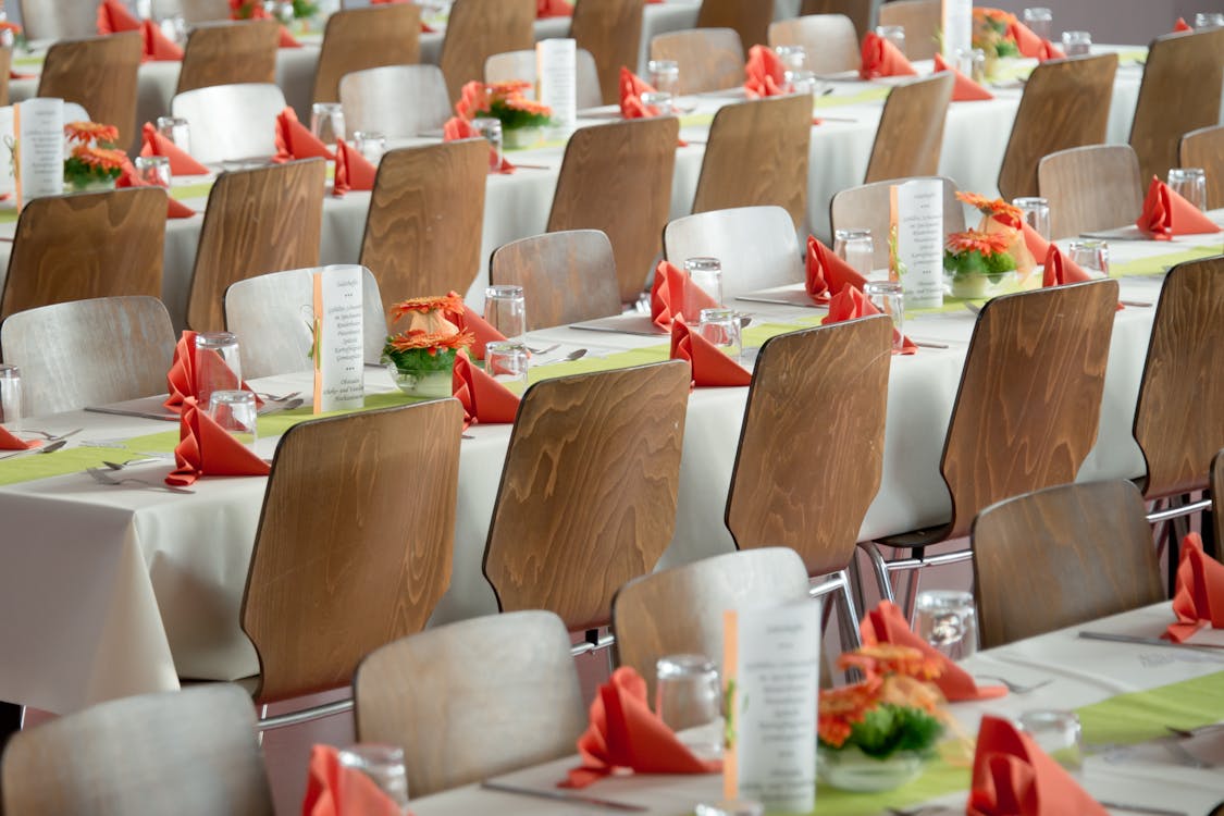 Elegant dining setup with red napkins and white chairs for a formal event.