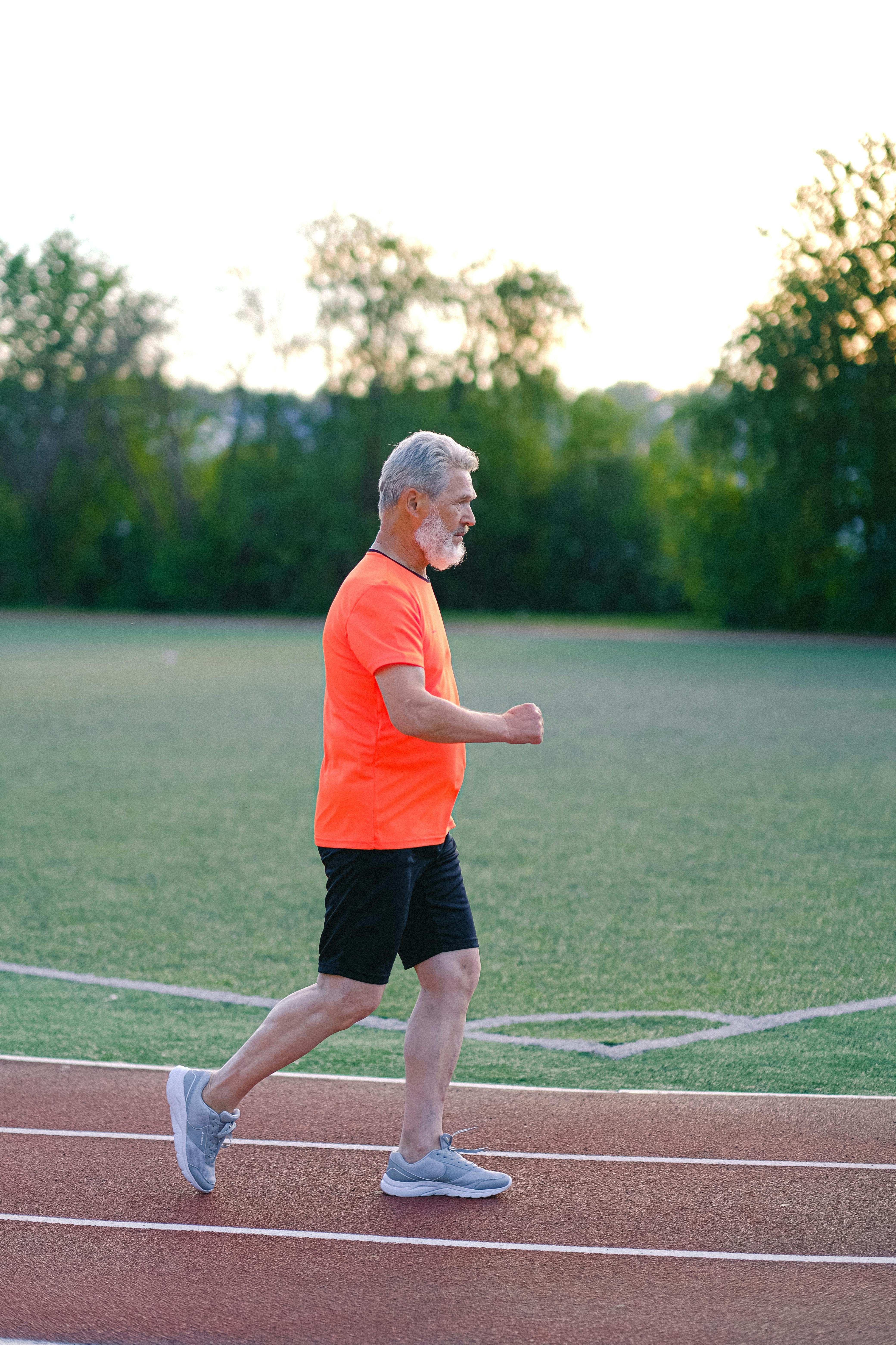 aged gray haired man running on stadium