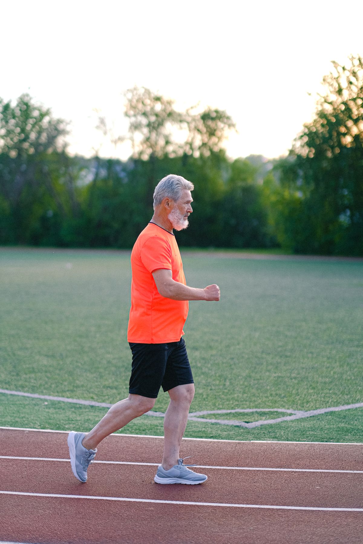 Aged gray-haired man running on a stadium track