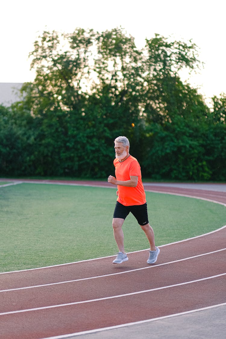 Senior Man Running On Racetrack In Stadium