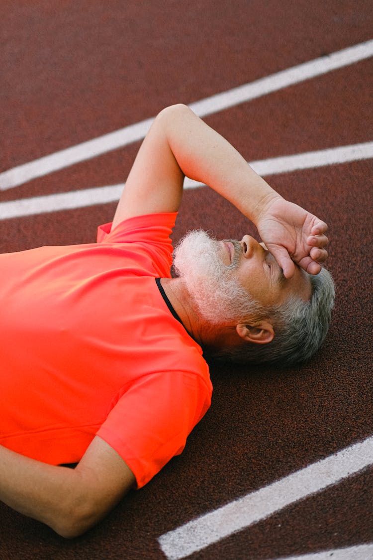 Tired Senior Man Resting And Lying On Racetrack