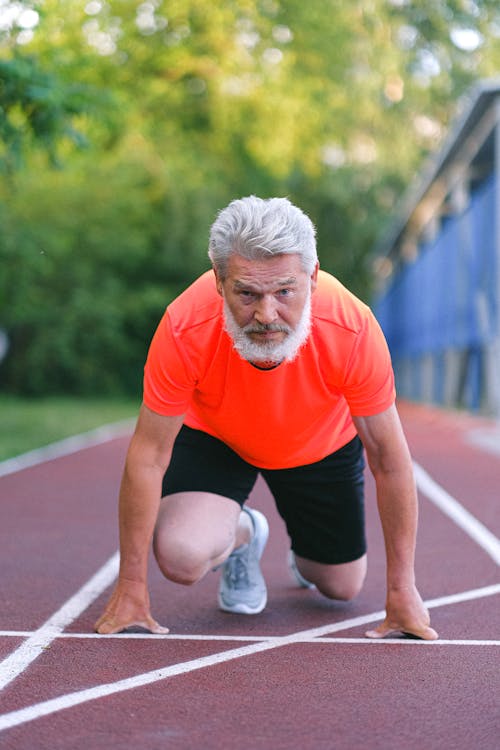 Free Strong senior sportsman preparing for competition in racing Stock Photo