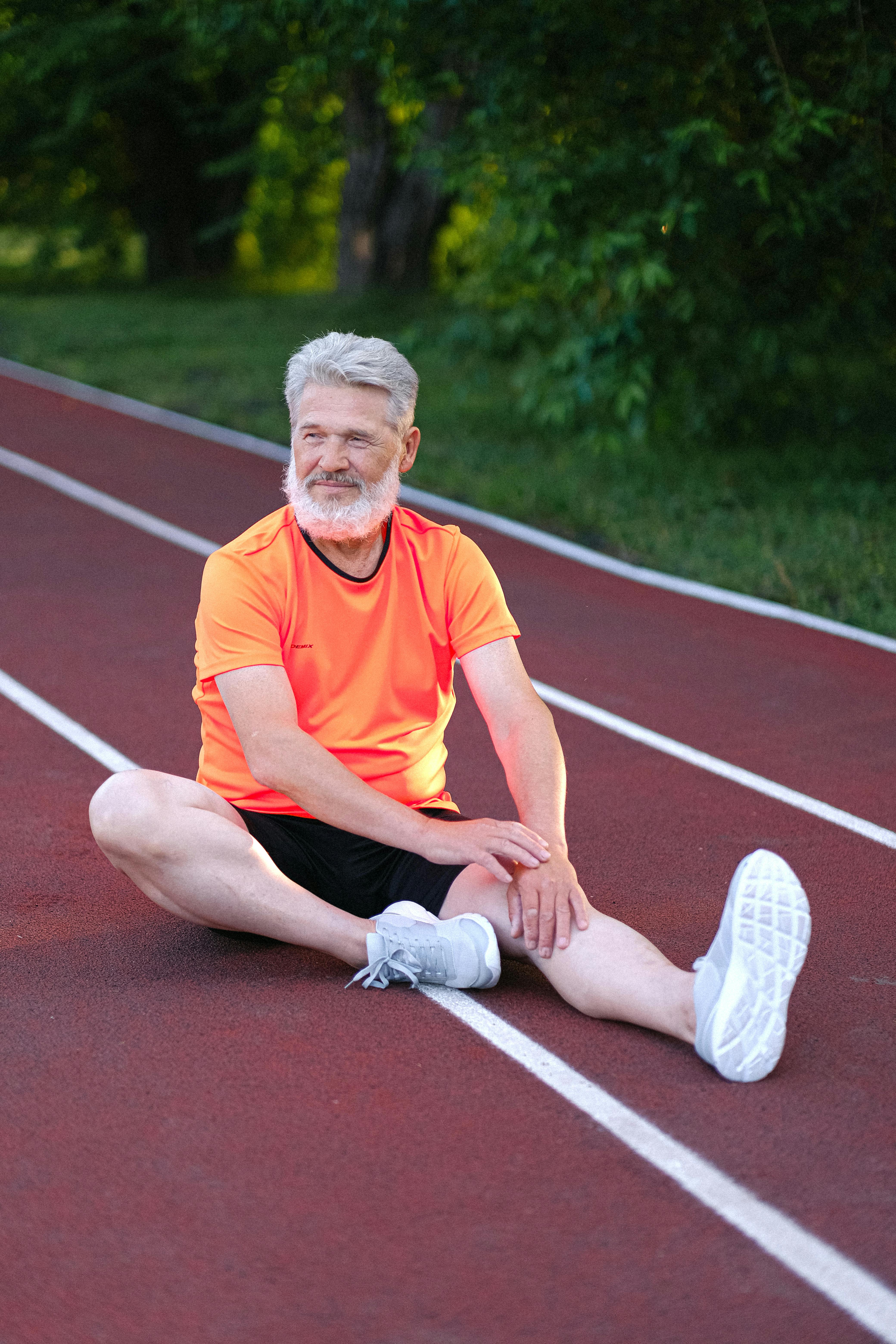 Happy senior man stretching in stadium