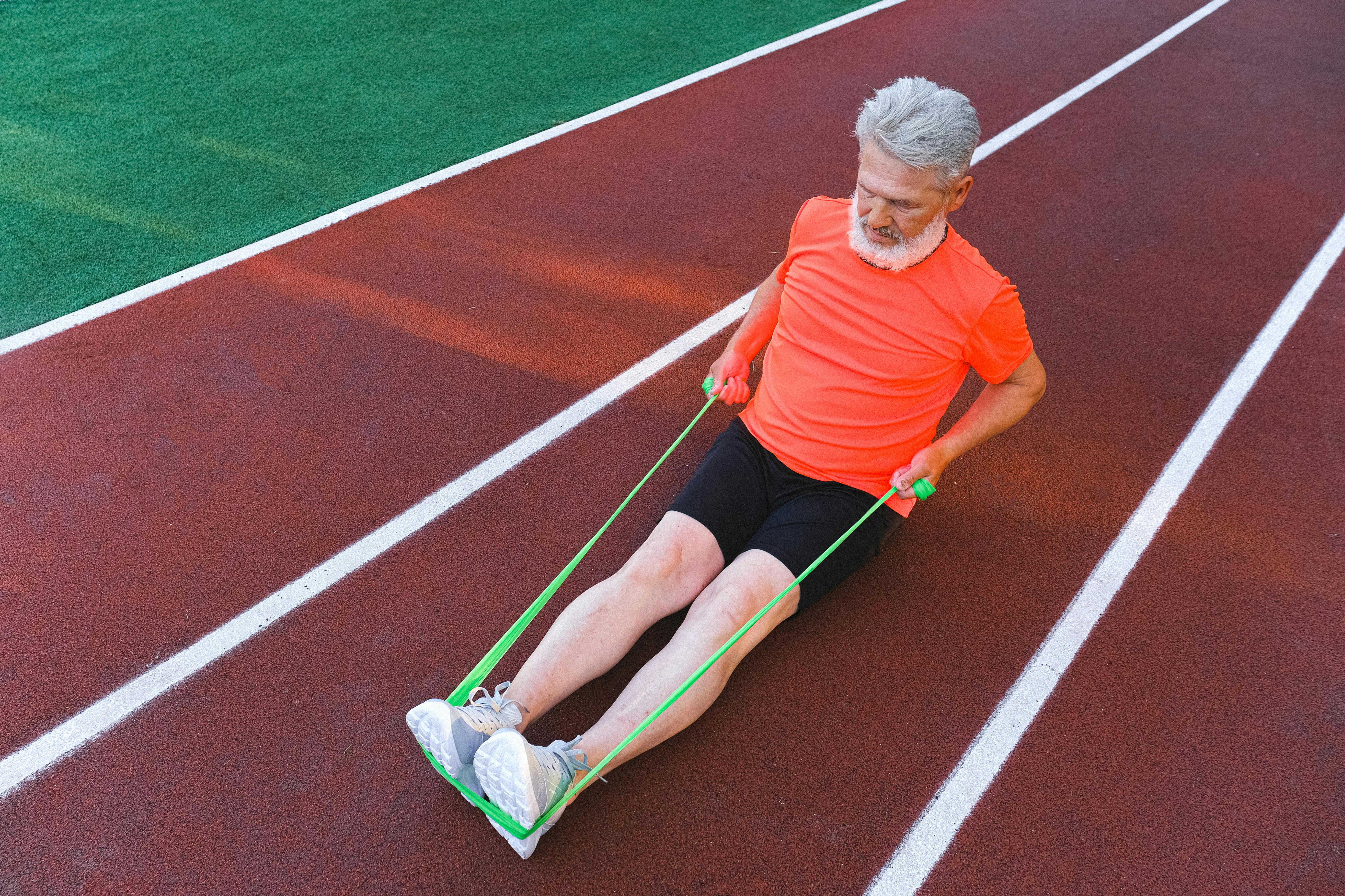 elderly athlete stretching legs with elastic rubber