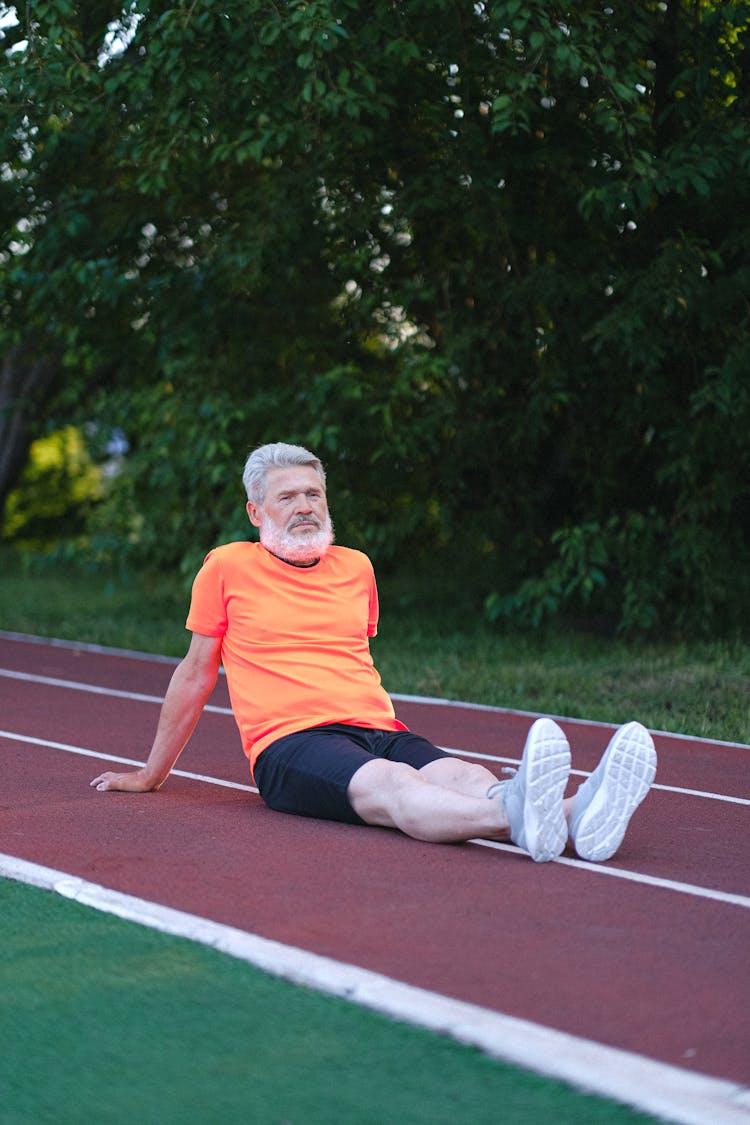 Senior Man In Sportswear Sitting On Stadium