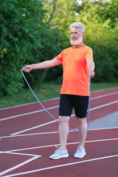 Elderly man in bright sportswear exercising with a jump rope outdoors on a sunny day.