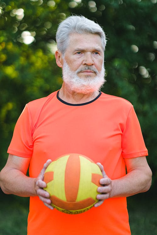 Serious aged man doing exercise with ball