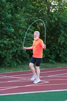 Elderly man jump roping on outdoor track for fitness and health.