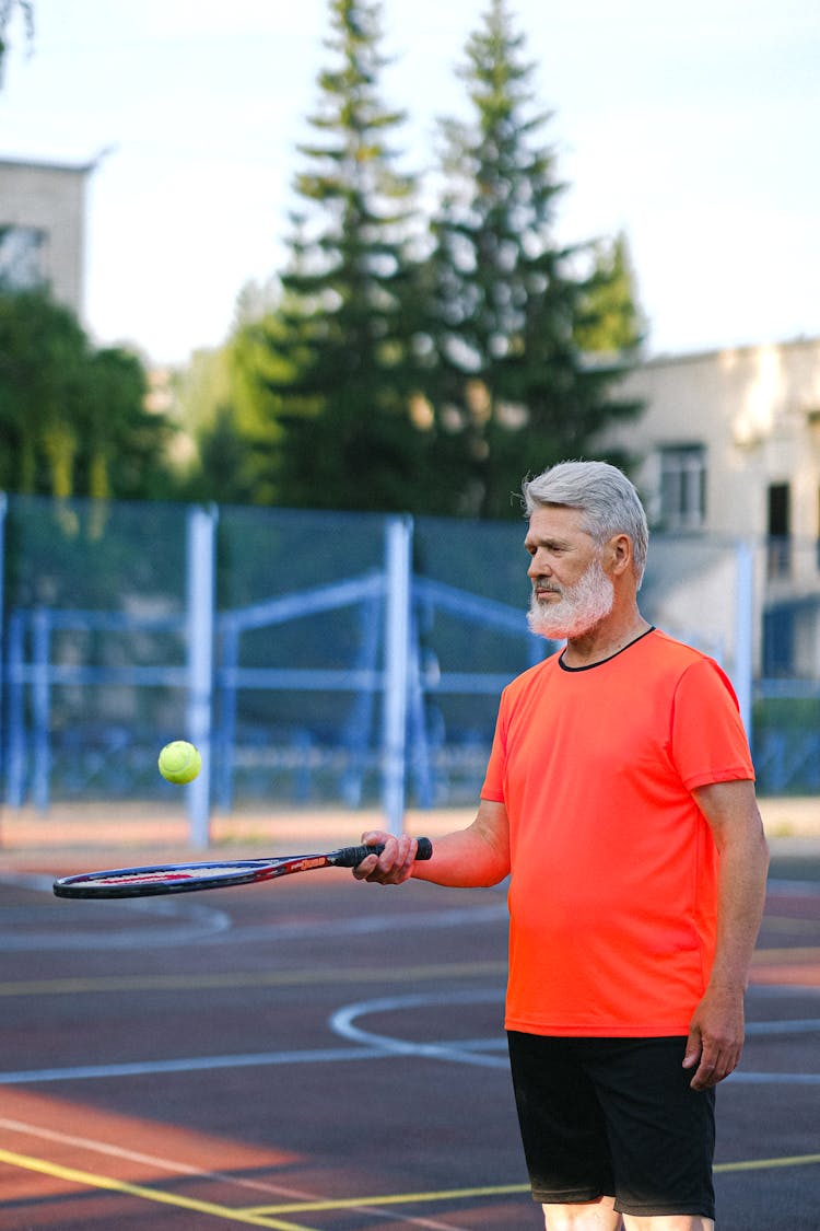 Senior Man Playing Tennis On Court