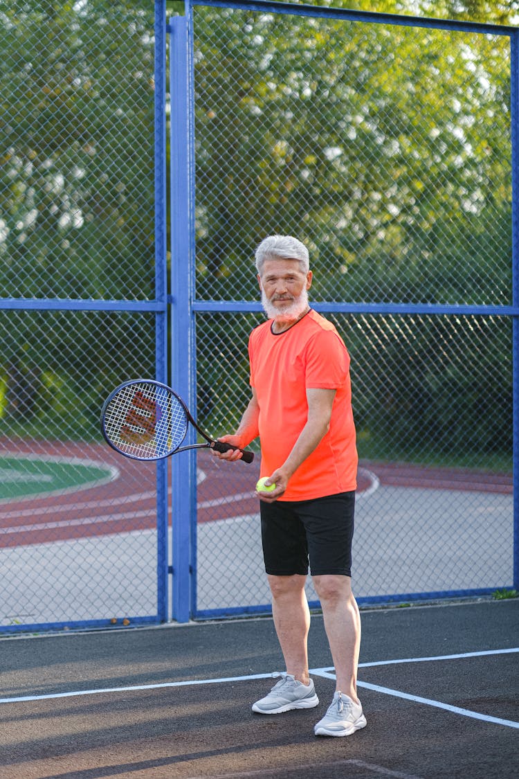 Senior Sportsman Playing Tennis On Court