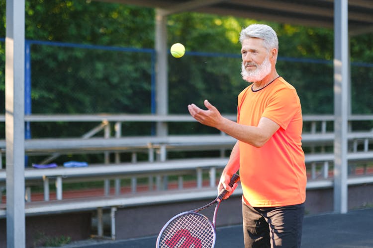 Focused Elderly Man Playing Tennis On Street