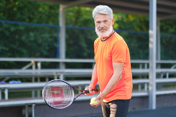 Cheerful Senior Man Playing Tennis On Street