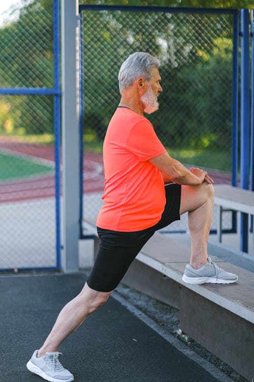 Senior sportsman stretching before training on street