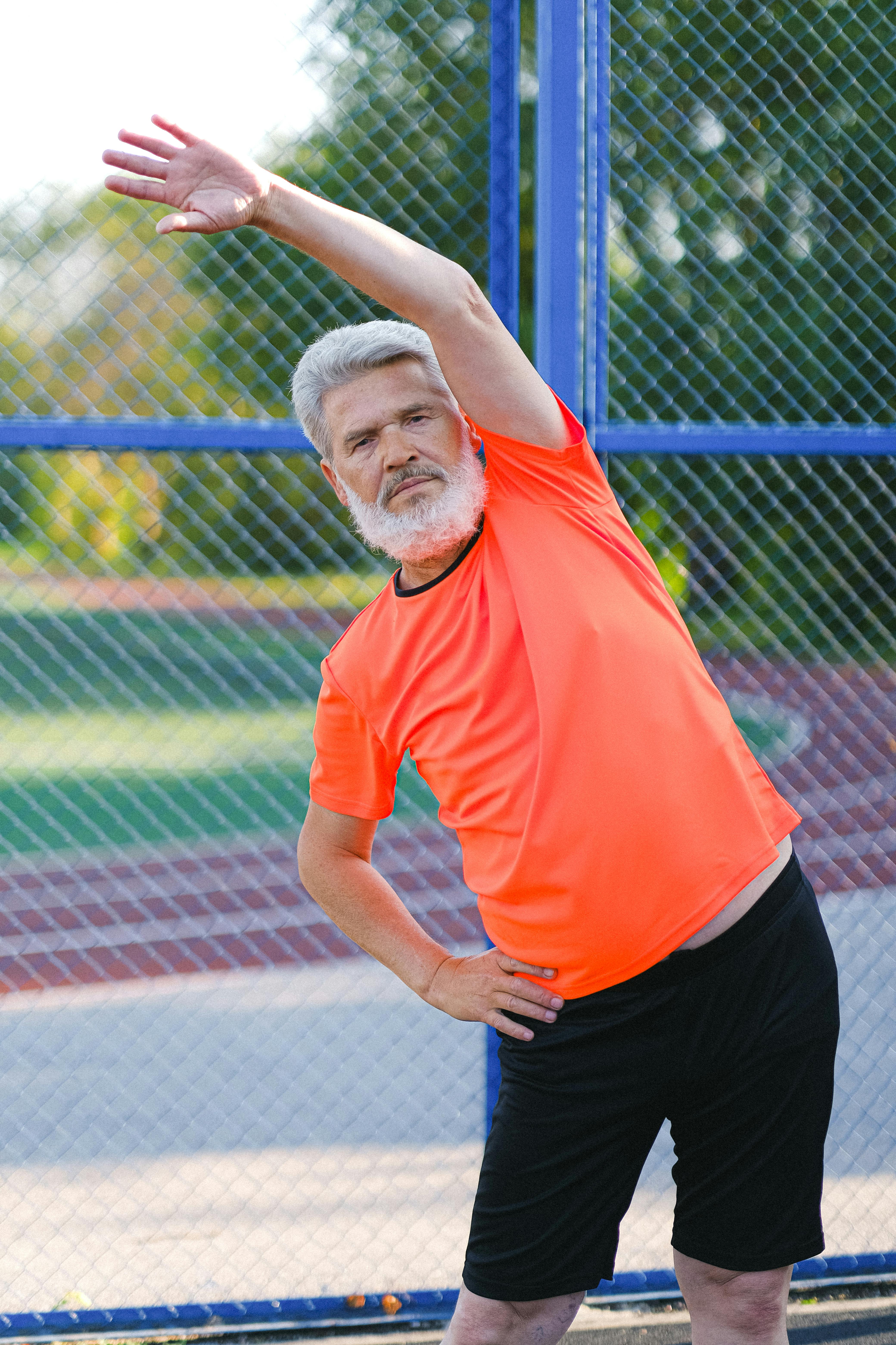 mature man stretching body on sports ground