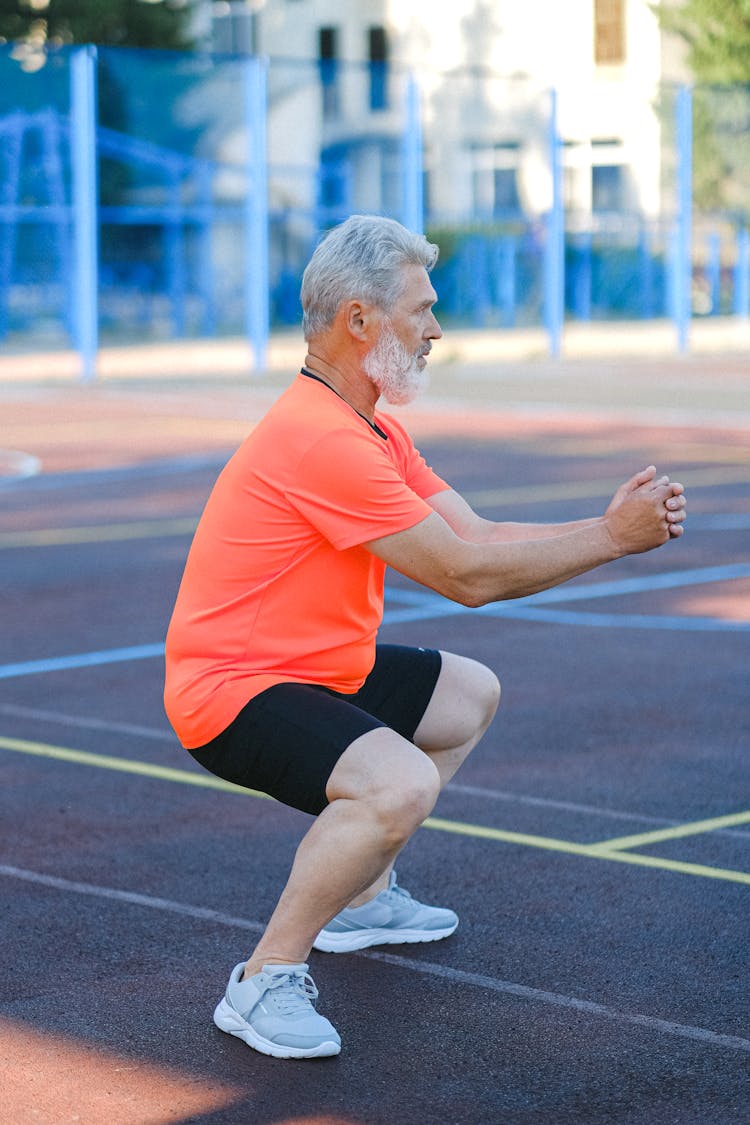 Mature Sportsman Doing Exercises On Stadium