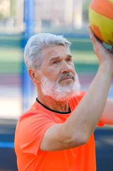 Elderly man in bright sportswear playing basketball, showcasing determination and fitness.
