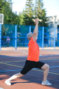 Elderly man in yoga warrior pose outdoors, focusing on fitness and wellness.