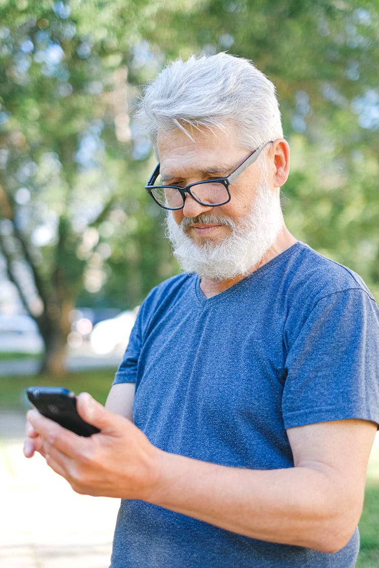 Senior Man In Blue T-shirt Holding A Smartphone