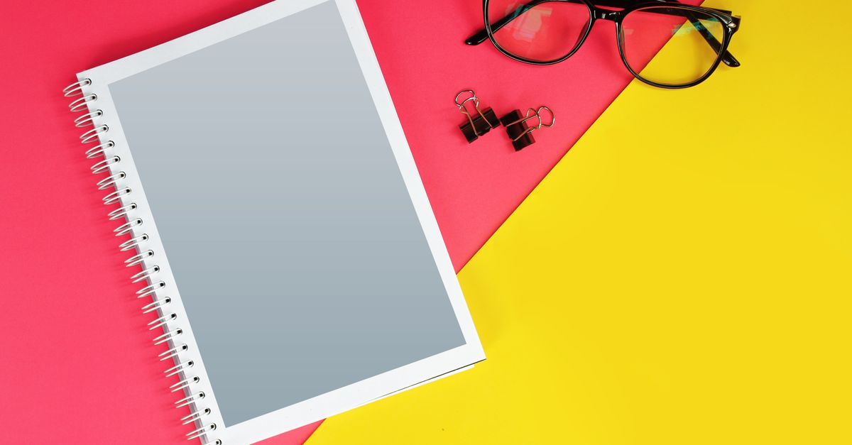 Vibrant office flat lay with notebook, glasses, and clips on colorful background.