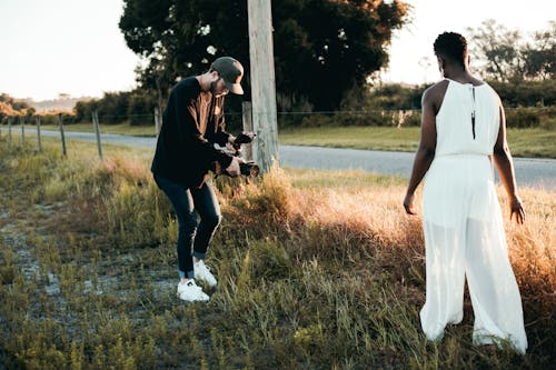 Man Filming the Person Walking on Grass Field 