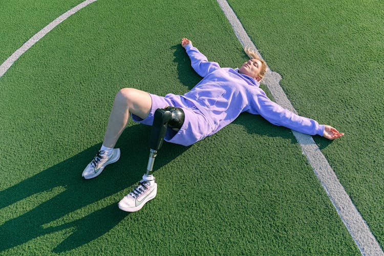 Woman With Prosthetic Leg Lying Down On The Lawn