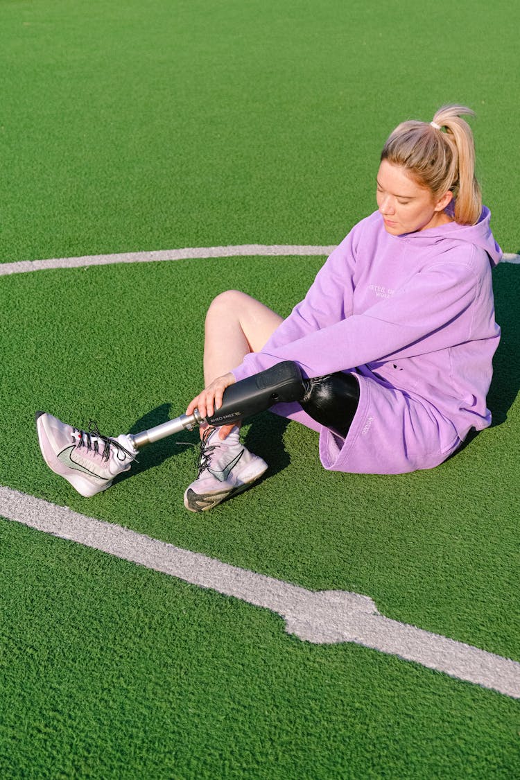 Young Disabled Woman Sitting On Sports Ground