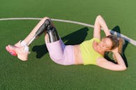 一名身着运动服、佩戴假肢的强壮女运动员正在运动场上进行腹肌练习